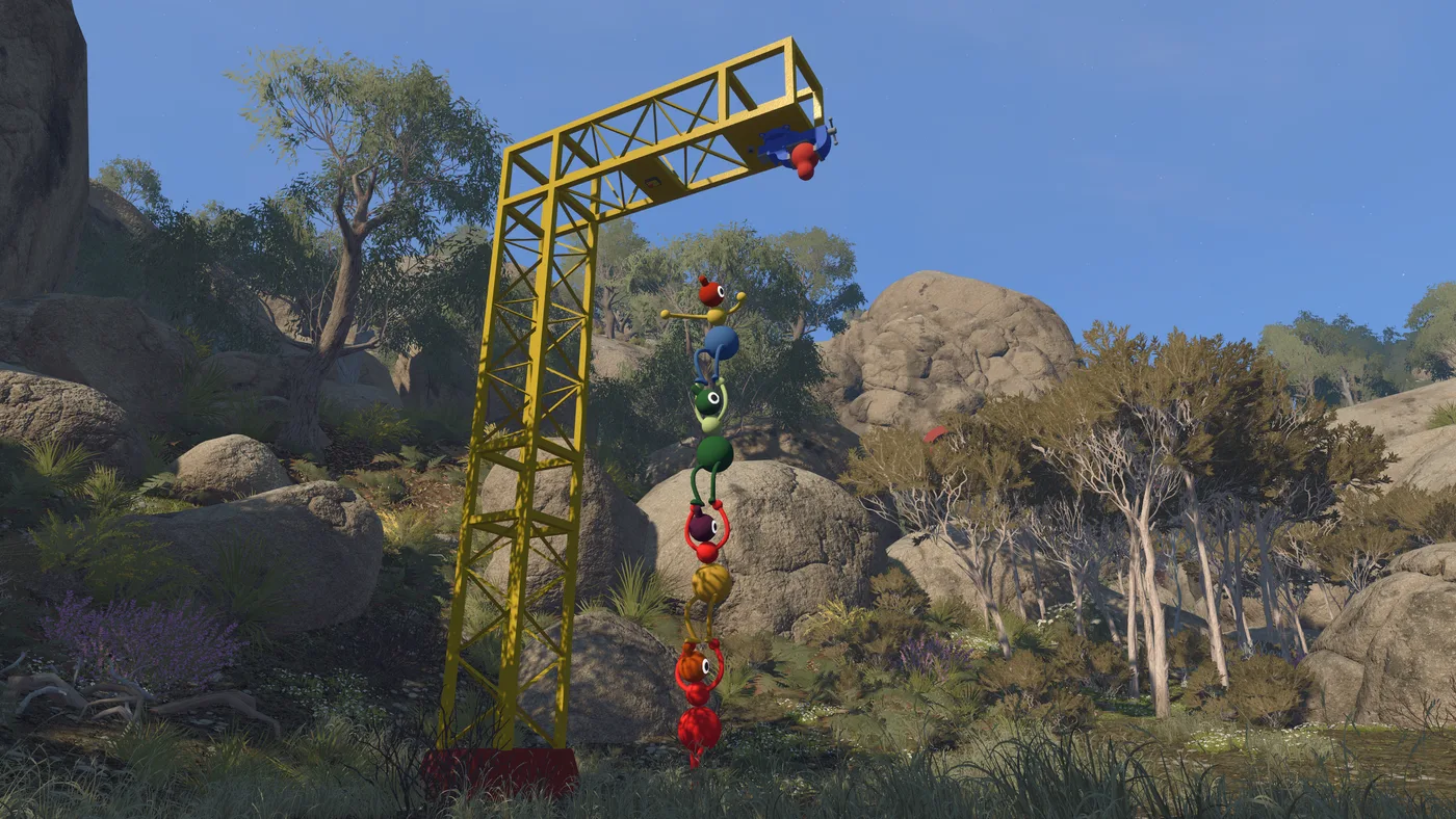 A tall yellow metal tower frame among granite boulders and eucalypts, with a chain of Big Walk characters climbing it one above another (June 2026 build)