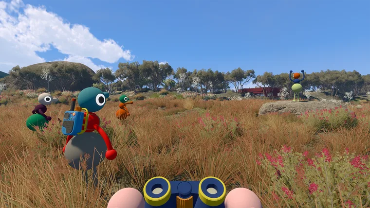 First-person view through a pair of blue and yellow binoculars, framing dry grassland. Two other characters stand in the grass ahead, one wearing a backpack (May 2025 build)