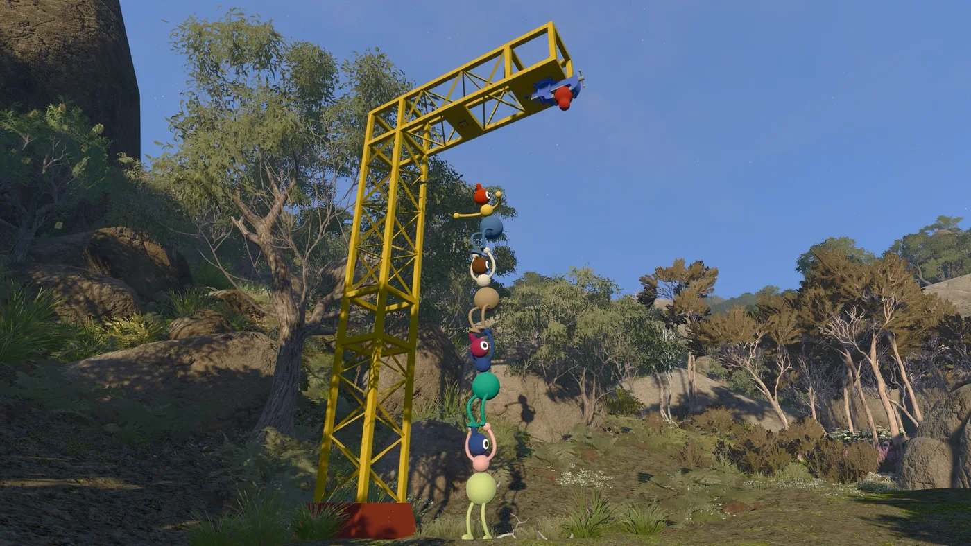 A tall yellow metal tower frame among granite boulders and eucalypts, with a chain of Big Walk characters climbing it one above another (May 2025 build)
