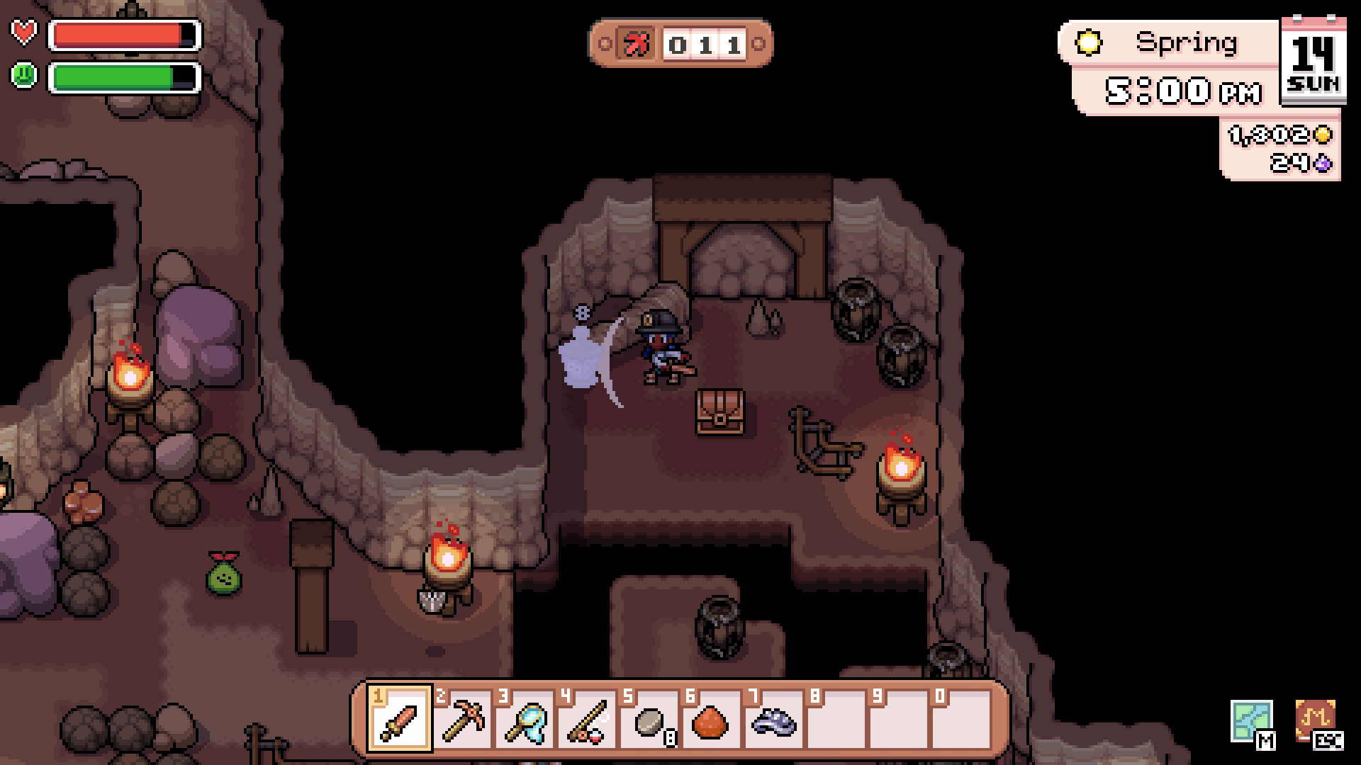 Player character swinging a sword at a slime in a torch-lit mine chamber.