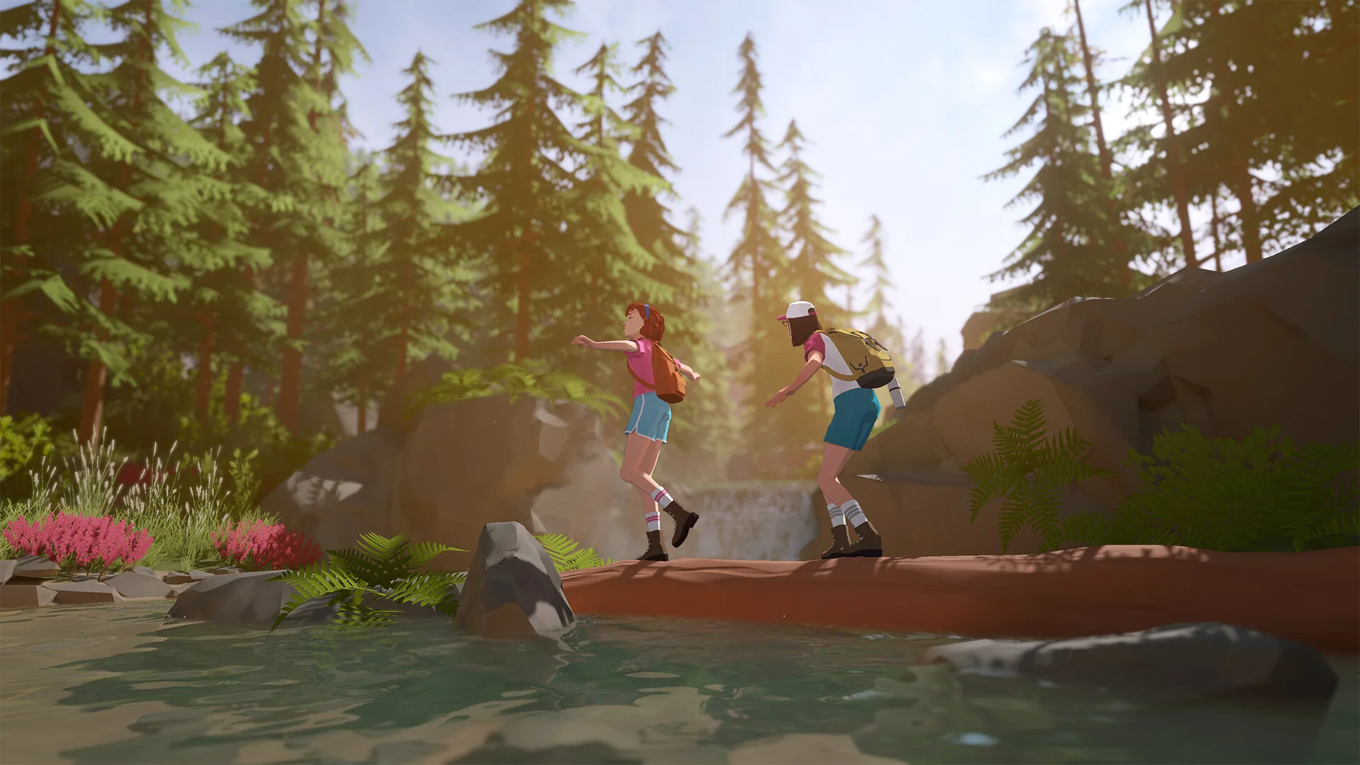 Two hikers cross a log over a forest creek among pink flowers and pines.