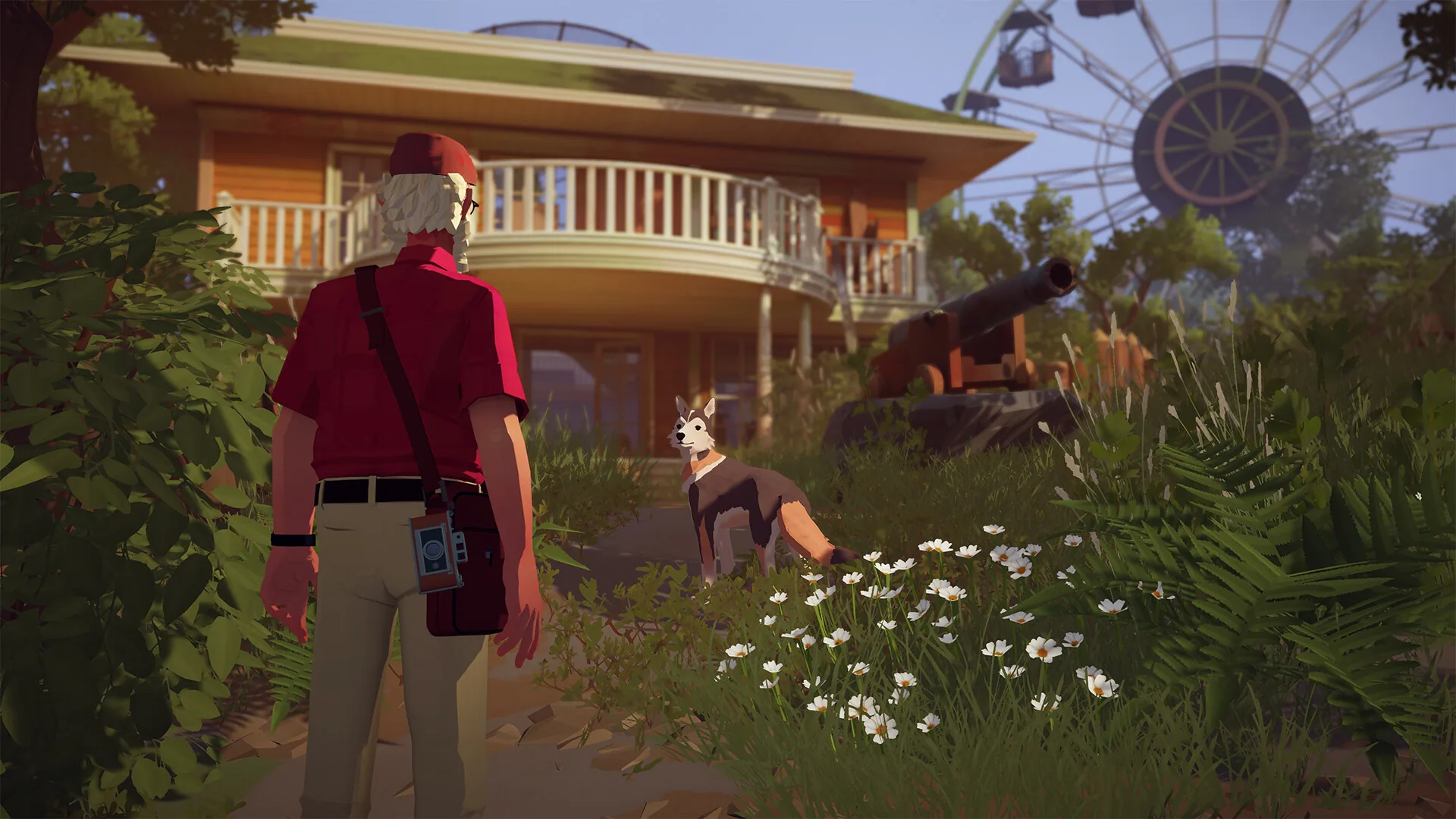 Alfred is seen from behind with a camera bag and a dog, near a wooden house, a ferris wheel, and a cannon in the grass.