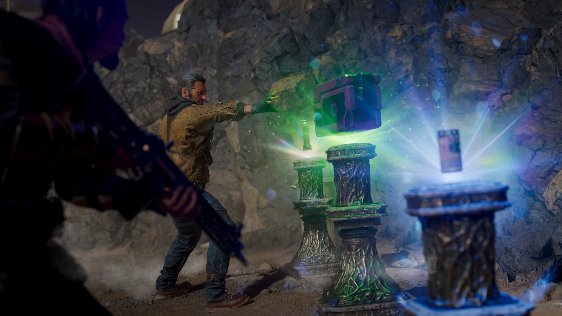 In a cave, an operator reaches toward a hovering crate and glowing artifacts on carved stone pedestals, a Zombies-mode ritual setup from the host game.