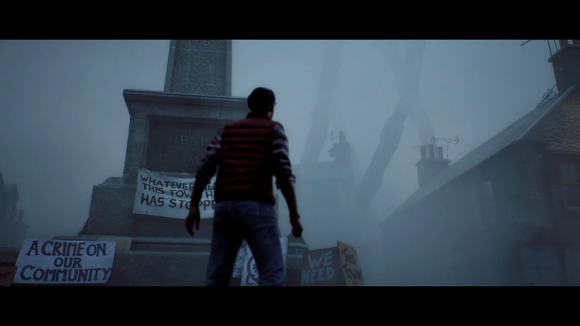 Simon Ordell stands at the Heart of St. Amelia monument among protest placards in thick fog.