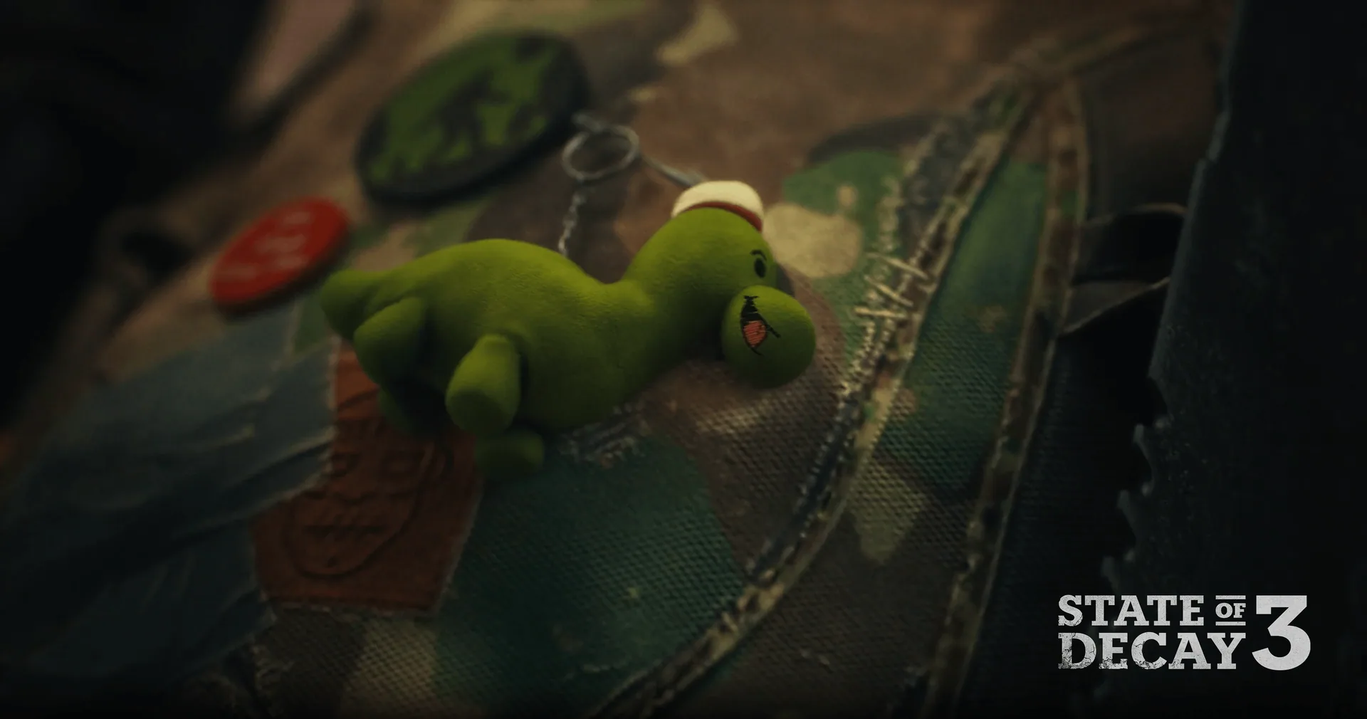 Green plush dinosaur keychain clipped to a survivor's patched camo backpack