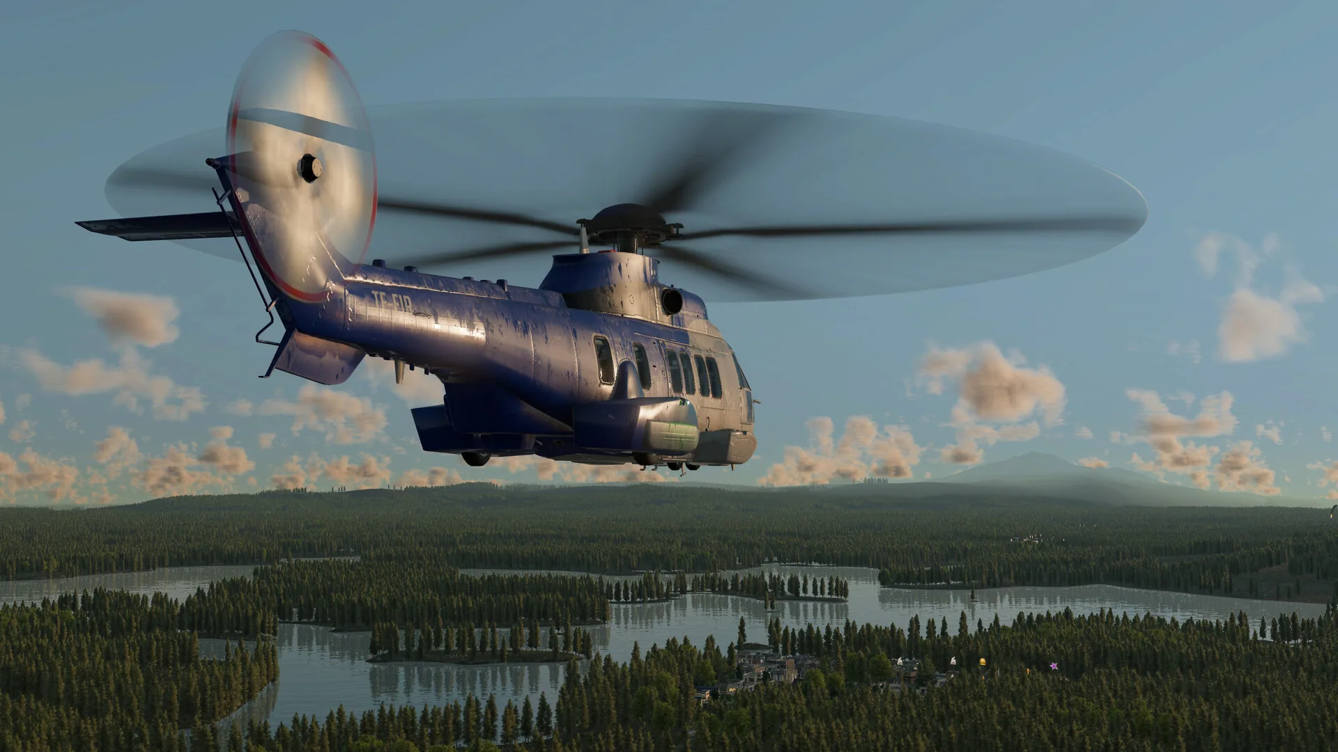 Blue transport helicopter flying over a lake-and-forest landscape at dusk