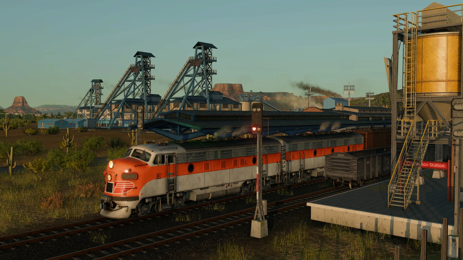 Orange-and-silver diesel locomotive at a desert industrial rail yard
